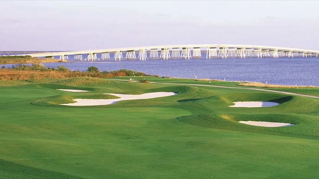Rum Pointe Seaside Links — a bunkered green with the bay and bridge beyond