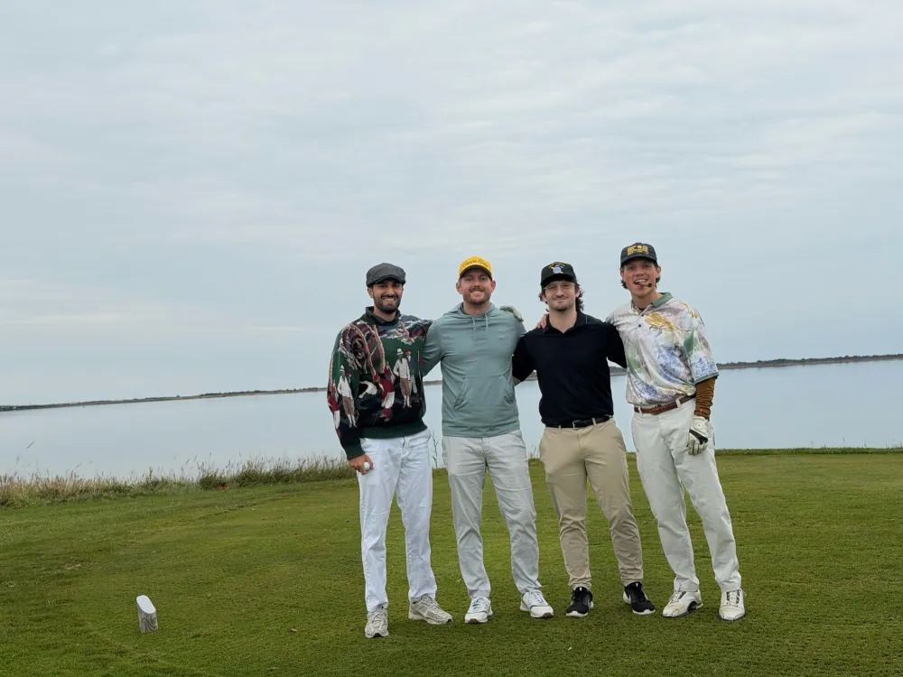 The crew lined up on the tee, the bay flat behind them