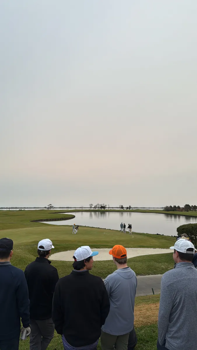 The group watching a putt drop across the pond in the last light