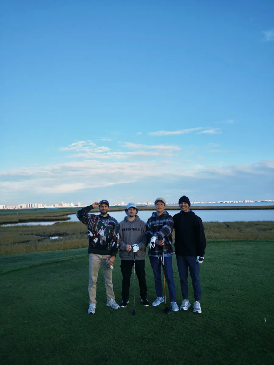 Four of the crew on the tee at dusk, the Ocean City skyline across the water